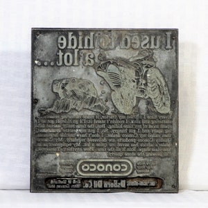 May include: A vintage metal printing plate with the text "I used to ride tractors" and an illustration of a tractor. The plate also features a turtle and the Conoco logo. The plate is rectangular and has a worn, aged appearance.