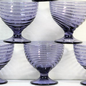 Puede incluir: Conjunto de cinco copas de vidrio morado con un dise&ntilde;o de espiral. Las copas tienen una base de vidrio transparente y un cuenco ancho.