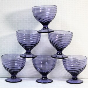 Puede incluir: Juego de seis copas de vidrio morado con dise&ntilde;o de espiral. Las copas est&aacute;n apiladas en forma de pir&aacute;mide.