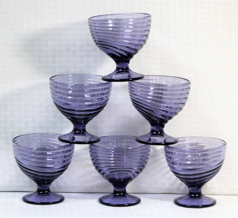Puede incluir: Juego de seis copas de vidrio morado con dise&ntilde;o de espiral. Las copas est&aacute;n apiladas en forma de pir&aacute;mide.