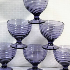Puede incluir: Seis copas de vidrio morado con un dise&ntilde;o de espiral. Las copas est&aacute;n apiladas en forma de pir&aacute;mide.