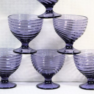 Puede incluir: Juego de seis copas de vidrio morado con dise&ntilde;o de espiral. Las copas tienen una base de vidrio transparente y un cuenco ancho.