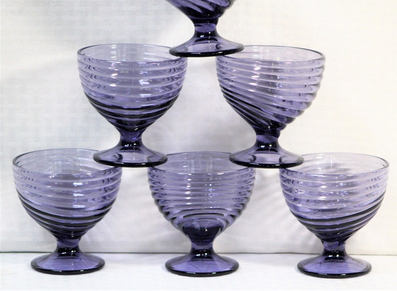 Puede incluir: Juego de seis copas de vidrio morado con dise&ntilde;o de espiral. Las copas tienen una base de vidrio transparente y un cuenco ancho.