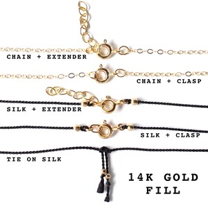 May include: Four different necklace styles are shown: a gold chain with an extender, a gold chain with a clasp, a black silk cord with an extender, and a black silk cord with a clasp. The last style is a black silk cord with a tie closure. All necklaces are made with 14k gold fill.