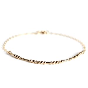 Peut inclure: Un bracelet délicat en or avec de petites perles rondes et de fines barres alternant le long de la chaîne.