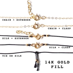 May include: Close-up of gold-filled necklace chains and silk cords with clasps and extenders. The image shows various necklace styles, including chain and silk options, with the text "14K GOLD FILL".