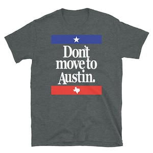 May include: A dark heather grey t-shirt with a white graphic that says "Don't move to Austin." The graphic also includes a white star and a white outline of the state of Texas.