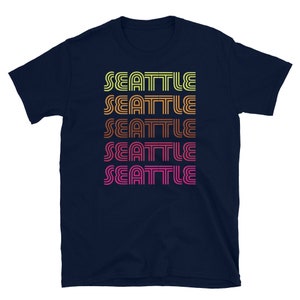 May include: Navy blue t-shirt with the word "Seattle" repeated five times in a retro, rainbow-colored font.