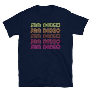 May include: Navy blue t-shirt with the text "SAN DIEGO" repeated five times in a retro, rainbow-colored font.