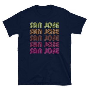 May include: Navy blue t-shirt with the text "SAN JOSE" repeated five times in a retro, rainbow-colored font.