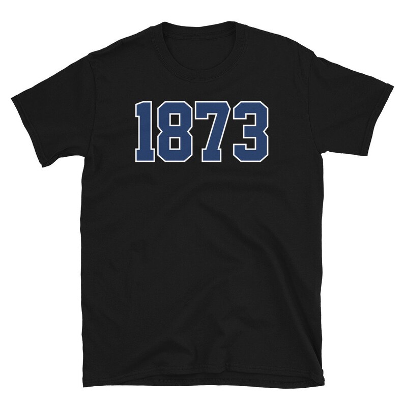 Puede incluir: Camiseta negra de manga corta con el n&uacute;mero 1873 impreso en azul en la parte delantera.