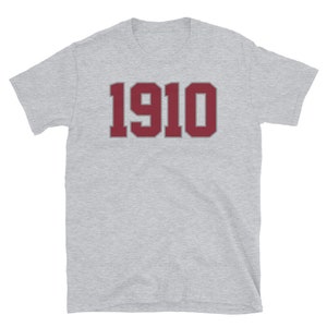 May include: A heather grey t-shirt with a maroon number "1910" printed on the front.