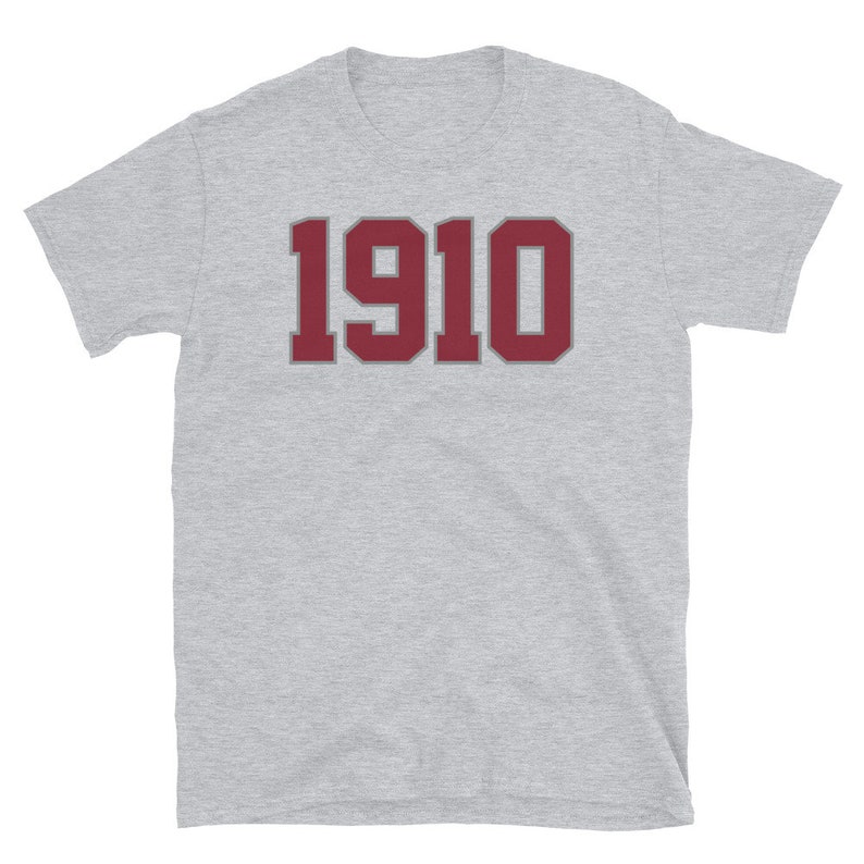 May include: A heather grey t-shirt with a maroon number "1910" printed on the front.