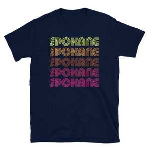 May include: Navy blue t-shirt with the word "SPOKANE" repeated five times in a retro, multi-colored font.