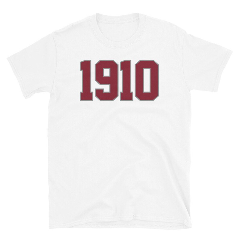 May include: White short-sleeved t-shirt with a maroon number "1910" printed on the front in a bold, varsity-style font.