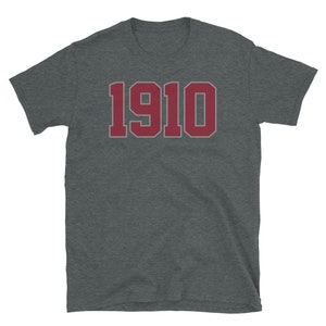 May include: A dark heather grey t-shirt with a red 1910 printed on the front.