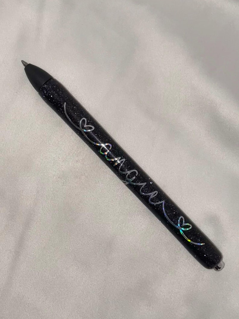 May include: A black glitter pen with silver lettering that says "Forever" with a heart symbol.