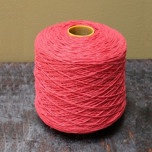 May include: A spool of bright red yarn, wound tightly and ready for use in crafting projects.