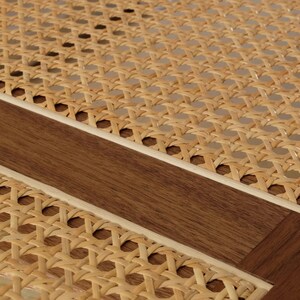 May include: A section of furniture featuring a light tan woven cane mesh pattern integrated into a dark brown wooden frame. The material displays a repeating octagonal weave structure with a smooth, polished wood border and light-colored trim.