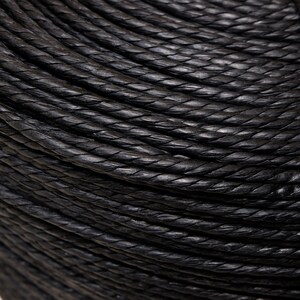 Puede incluir: Primer plano de un cordón de cuero trenzado negro. El cordón está enrollado apretado y muestra los intrincados detalles del trenzado.