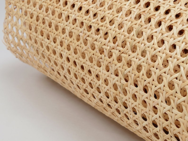 May include: A roll of light beige cane webbing featuring a consistent octagonal woven pattern. The material is made of thin, flexible strips of natural plant fiber, creating a semi-transparent, open-grid texture across the entire surface.