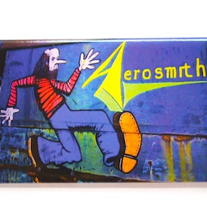 May include: A blue and yellow Aerosmith magnet with a cartoon illustration of a person running with a large shoe.