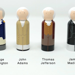 May include: Four wooden peg dolls representing U.S. Founding Fathers: George Washington, John Adams, Thomas Jefferson, and James Madison. Each doll is painted with historical attire and hairstyles, with names below.