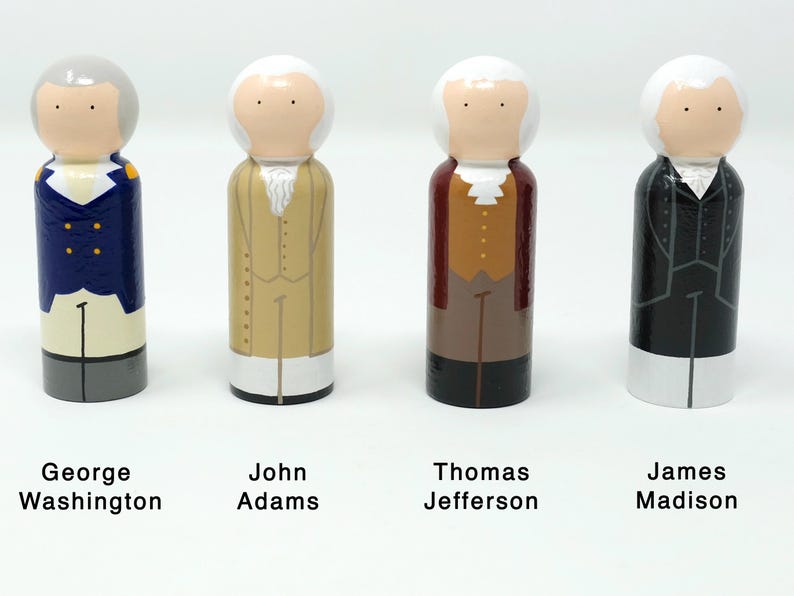 May include: Four wooden peg dolls representing U.S. Founding Fathers: George Washington, John Adams, Thomas Jefferson, and James Madison. Each doll is painted with historical attire and hairstyles, with names below.