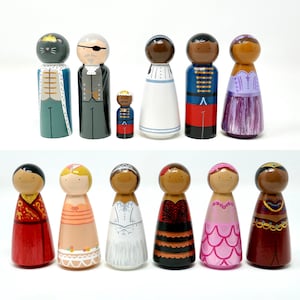May include: A collection of hand-painted wooden peg dolls. The dolls feature various designs, including a cat king, a pirate, and figures in dresses and uniforms. The color palette includes blue, red, white, and gold. These dolls are suitable for display or play.