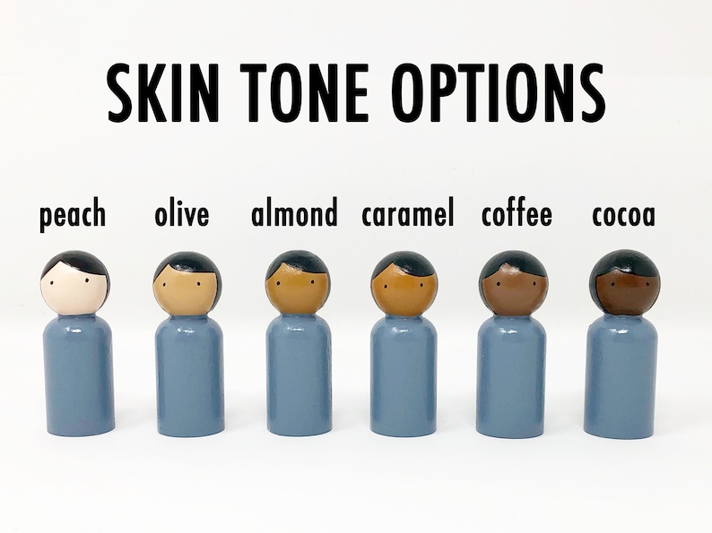 May include: Six wooden peg dolls with varying skin tones are displayed: peach, olive, almond, caramel, coffee, and cocoa. Each doll has a blue body and black hair. The text "SKIN TONE OPTIONS" is above the dolls.