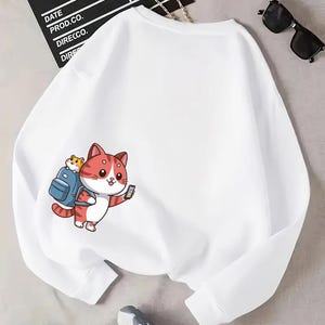 Adventure Cat Sweatshirt – Cute White Pullover with Cartoon Cat and Backpack Design.