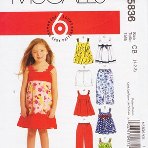 Può includere: Un cartamodello per abbigliamento per bambini, con una bambina che indossa un vestito floreale rosso e bianco. Il cartamodello include istruzioni per realizzare una varietà di abiti, pantaloni e gonne. Il numero del cartamodello è M5836/CB.
