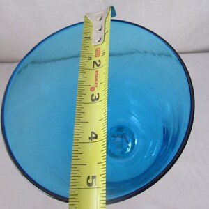 K&ouml;nnte beinhalten: Eine leuchtend blaue Glasschale mit kreisf&ouml;rmiger &Ouml;ffnung, von oben betrachtet. Ein gelbes Stanley-Ma&szlig;band liegt &uuml;ber der Mitte und zeigt einen Durchmesser von etwa 13,3 cm f&uuml;r den breiten Rand der Schale an.