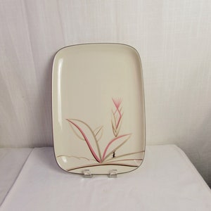 May include: A rectangular serving platter with a cream-colored background and a stylized floral design in shades of pink, brown, and black.