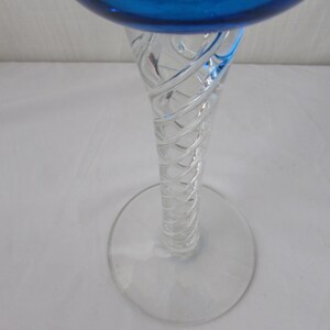 K&ouml;nnte beinhalten: Ein Glas-Kelch mit einer leuchtend blauen Schale und einem klaren, transparenten Stiel. Der Stiel ist mit einem komplexen, spiralf&ouml;rmigen wei&szlig;en Glasfadenmuster versehen, das sich vom runden, klaren Glasfu&szlig; bis zur Schale nach oben windet.
