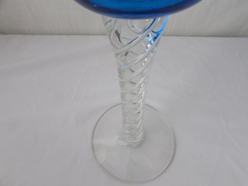 K&ouml;nnte beinhalten: Ein Glas-Kelch mit einer leuchtend blauen Schale und einem klaren, transparenten Stiel. Der Stiel ist mit einem komplexen, spiralf&ouml;rmigen wei&szlig;en Glasfadenmuster versehen, das sich vom runden, klaren Glasfu&szlig; bis zur Schale nach oben windet.