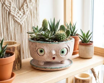 Maceta de cerámica de ojos verdes: una sutil sonrisa y un botón, una maceta caprichosa hecha a mano.