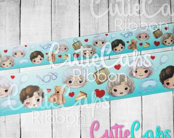 May include: A turquoise ribbon with a repeating pattern of cartoon faces, hearts, and suitcases. The faces are of a woman with white hair and a man with brown hair. The text "Cutie Caps Ribbon" is printed on the bottom of the image.