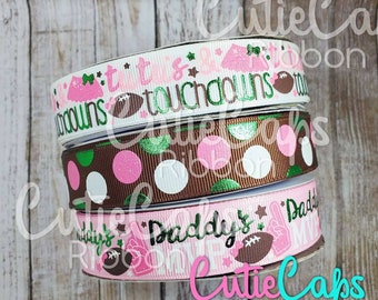 May include: Three rolls of pink, brown, and white ribbon with football and star designs. The ribbon reads "It is all touchdowns" and "Daddy's little MVP".