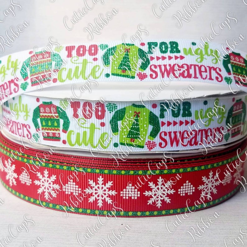 May include: Two rolls of Christmas ribbon. The top roll is white with green and red accents. It features a repeating pattern of ugly Christmas jumpers with the text "Too cute for ugly sweaters". The bottom roll is red with green and white accents. It features a repeating pattern of snowflakes.