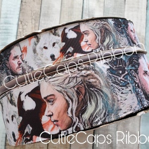 May include: Two rolls of white and brown ribbon with a printed design of characters from the TV show Game of Thrones. The ribbon features images of Daenerys Targaryen, Jon Snow, and a direwolf.