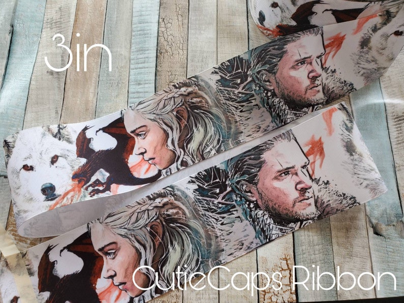 May include: White satin ribbon with a printed design of characters from the TV show Game of Thrones. The characters are Daenerys Targaryen and Jon Snow. The ribbon is 3 inches wide.