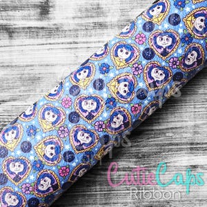May include: Blue and white fabric with a repeating pattern of a girl with black hair in a heart-shaped frame. The fabric has a textured surface and a subtle sparkle.