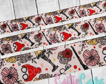 May include: A close-up of a white ribbon with a repeating pattern of red and pink flowers, glasses, and a person wearing a red hat and black stockings. The ribbon is on a white wooden surface. The text "Cutie Caps Ribbon" is visible at the bottom of the image.