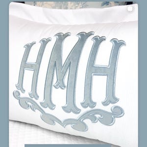 Peut inclure: Oreiller blanc avec un monogramme en velours bleu clair des lettres "HMH" et une bordure décorative. Le texte "Le monogramme Collette avec juste la bordure inférieure" est en haut, et "Velours bleu clair" en bas.