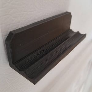 May include: A black plastic shelf designed to be mounted on a refrigerator door.