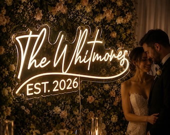 May include: A custom neon sign mounted on a floral wall, featuring the illuminated white script text The Whitmores and the text EST. 2026 below it. The sign is constructed from clear acrylic with a glowing light effect.