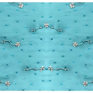 May include: A turquoise fabric with a repeating pattern of small silver flowers and silver beads.