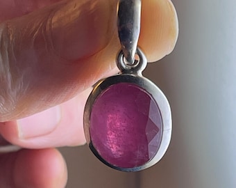 May include: A silver pendant featuring a large, oval-shaped, faceted, pink gemstone.