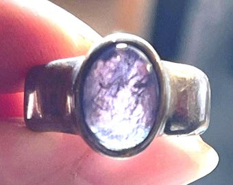 May include: A silver ring with a large oval-shaped purple gemstone.